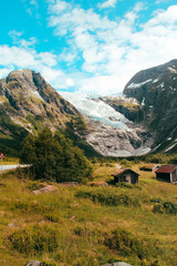 Fototapeta na wymiar Blick auf einen Gletscher in Norwegen mit Holzhütten im Vordergrund / View at a glacier in norway with cabins in the foreground