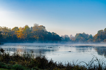 the lake is surrounded by autumn trees reflected in the mirror surface of the lake, quiet morning