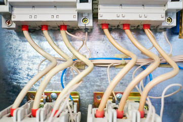 Two electric three-phase switches connected by wires on a metal background.