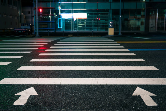 The Red Traffic Light On A Crosswalk At Night On Wet Asphalt