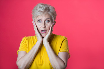 stylish woman at the age with a short haircut in a yellow T-shirt on a red background