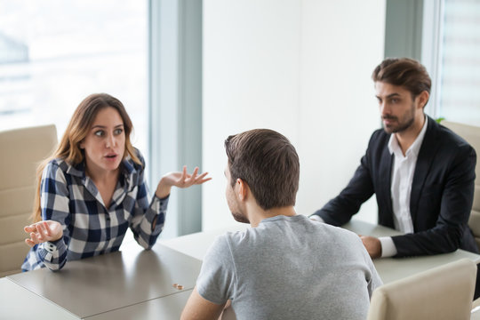 Unhappy depressed young couple at meeting with lawyer about divorce. Nervous emotional wife sitting in counselor office, arguing with husband, blaming, breaking up.