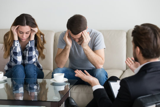 Depressed frustrated couple family touching head at meeting with psychologist counselor. Emotional breakdown, feels exhausted, desperate, unhappy. Problems in family, distress, distrust, break up
