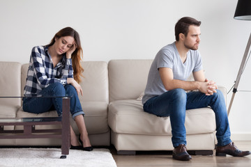 Sad, desperate, frustrated young couple no desire to talk after quarrel. Man sitting with back to...