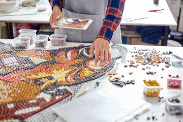 Crop man composing mosaic pieces