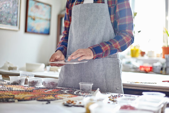Anonymous man using tablet while composing mosaic - Powered by Adobe