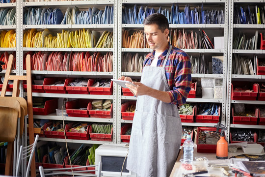 Young man using tablet in mosaic workshop