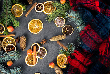 Fototapeta na wymiar Sliced dried orange with christmas pine branches and scarf on dark texture surface. Holiday background.