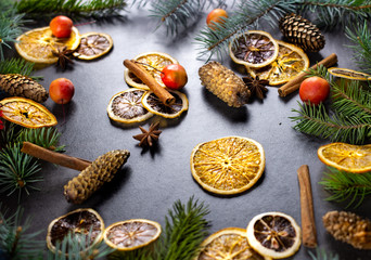 Sliced dried orange with christmas pine branches on dark texture surface. Holiday background.