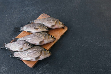 Cooking fish. Fresh small carps on the table on a wooden Board close-up.