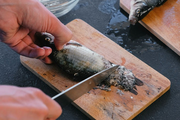 Man cleans carp from the scales. Close-up hands. Cooking a fish.
