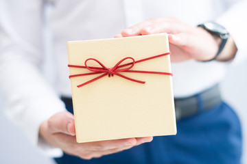 Closeup of man holding gift box. Person greeting someone. Gift concept. Isolated cropped view on grey background.