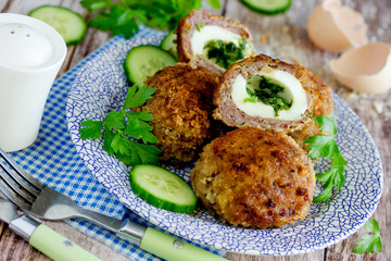 Meatballs stuffed with boiled eggs and green herbs butter in bread crumbs