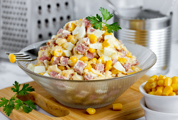 Mixed salad from salami sausage, cheese, boiled egg and canned corn with mayonnaise dressing