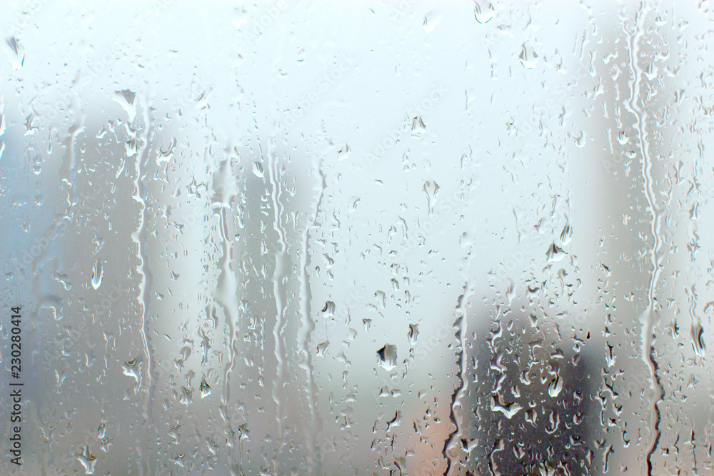 Wall mural Rain drops on window glasses surface with cloudy background.