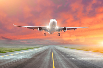 Naklejka na ściany i meble Flying and traveling, sunset airplane landing runway airport.