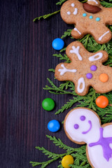 Fototapeta na wymiar Cute Christmas gingerbread cookies and multicoloured sweets against the dark background