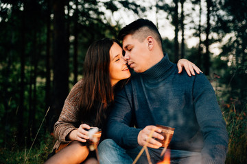 Summer Camp Fire. Tourism sexy photo. Cute couple kissing in the park on a sunny day. Adventure concept. Man and woman kissing. Couple in love. Camping fire. Love story. Romance lovers. Fashion photo.