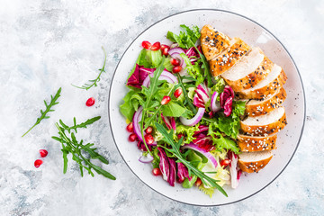 Grilled chicken breast, fillet and fresh vegetable leafy salad with arugula and pomegranate on plate