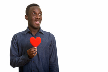 Young happy African man smiling with red heart on chest while th