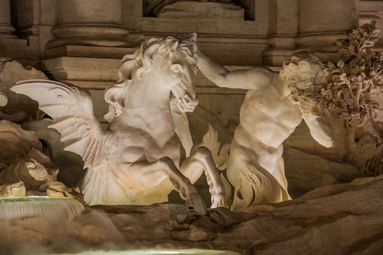 Mythological Triton tames a Hippocampus and blowing a conch, in the wonderful Trevi Fountain at night in Rome (18th century)
