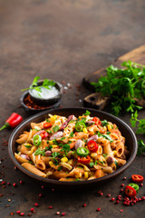 Spicy pasta penne bolognese with vegetables, beans, chili and cheese in tomato sauce
