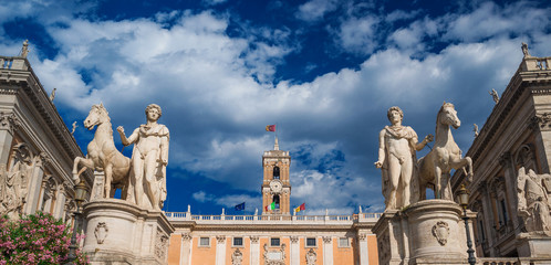 Capitoline Hill with ancient roman statues and renaissance clocktower with clouds, in the very...