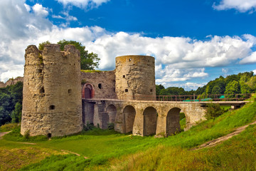 Fototapeta na wymiar Monument of medieval defensive architecture. A stone towers with closed gate between them, bridge with arches over the moat. Koporye Fortress, Leningrad District, Saint Petersburg, Russia.
