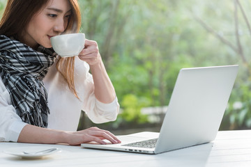 Beautiful young teenage woman freelance work with laptop with a cup of latte on sun light, freelance lifestyle conceptual