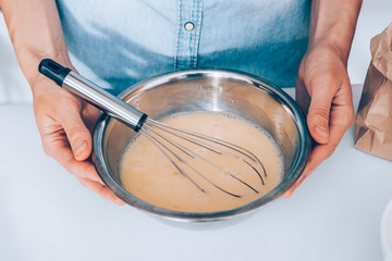Female's hands holding metal bowl of whipped eggs