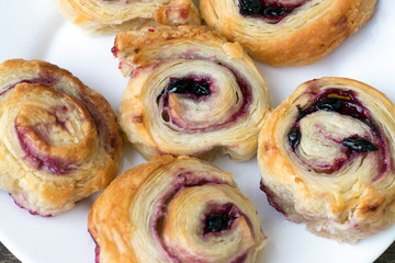 Appetizing buns with jam in the form of a roll on a light dish, close-up