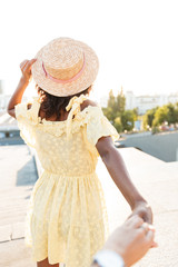 Fototapeta premium Back view photo of african young woman walking outdoors
