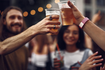 Cheers my friend. Close up of male hands clinking cups of cold beer