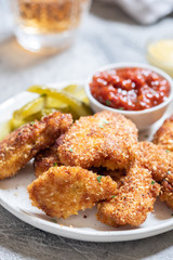 Fried crispy chicken nuggets with ketchup and pickles