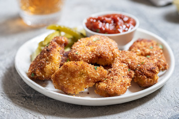 Fried crispy chicken nuggets with ketchup and pickles