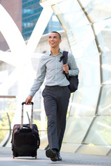 Full body young businessman walking with travel bags