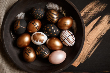 golden decorated easter eggs and black wooden background