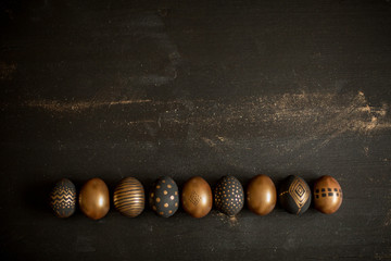 golden decorated easter eggs and black wooden background