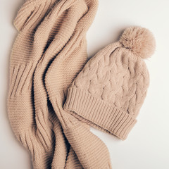 Knitted scarf a pipe or a collar from warm threads and beige cap with a pompon. Clothes for autumn and winter. close-up