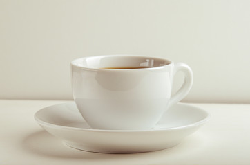 Mug with warm tea on a white table on white background.
