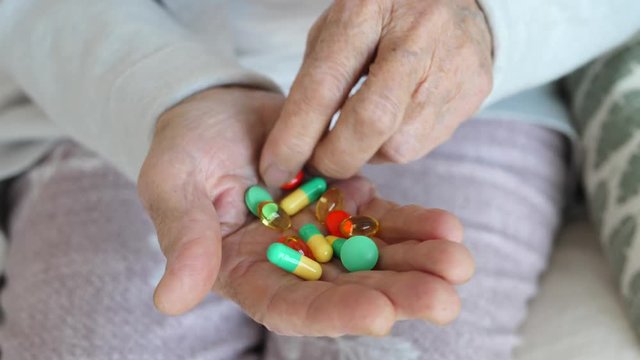 Old Hand Of Grandmother Holding Colorful Pills