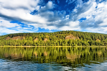 Scenic view on sloped green forestry bank of russia east siberia Yenisei river near krasnoyarsk city with scenery blue sky clouds reflection on still water wonderland panoramic nature background