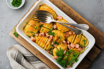 Baked potatoes with ham, herbs and breadcrumbs on gray light background. Scandinavian cuisine. Top view.