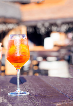 Glass of delicious Aperol Spritz cocktail on blurred background