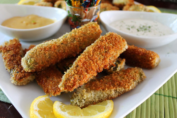 Deep fried dill pickles, with dipping sauce, and sour cream and chives. White plate and bowls, colorful toothpicks.