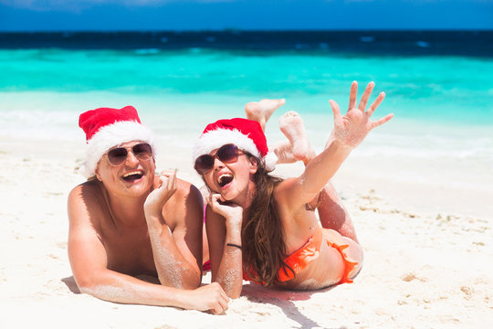 couple in santa hats celebrating christmas at the beach