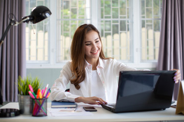 Beautiful young Asia woman working with laptop in her office