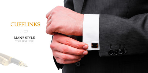 Elegant young fashion man looking at his cufflinks while fixing them.  Creative layout man in black jacket holds cufflinks on isolated background.  Flat lay. Your text here.