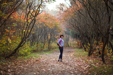 Fototapeta premium Girl in a yellow autumn forest. Beautiful young woman walks along the path of the autumn forest.