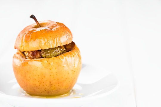 Fresh baked stuffed apple with walnut, almond, raisin, sultana, butter, sugar, cinnamon, traditional autumn and winter dessert, copy space on the right side (Selective Focus on the front of the apple)